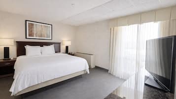 Een hotelkamer met een groot bed, een flatscreen televisie, een schilderij aan de muur en een raam met gordijnen.