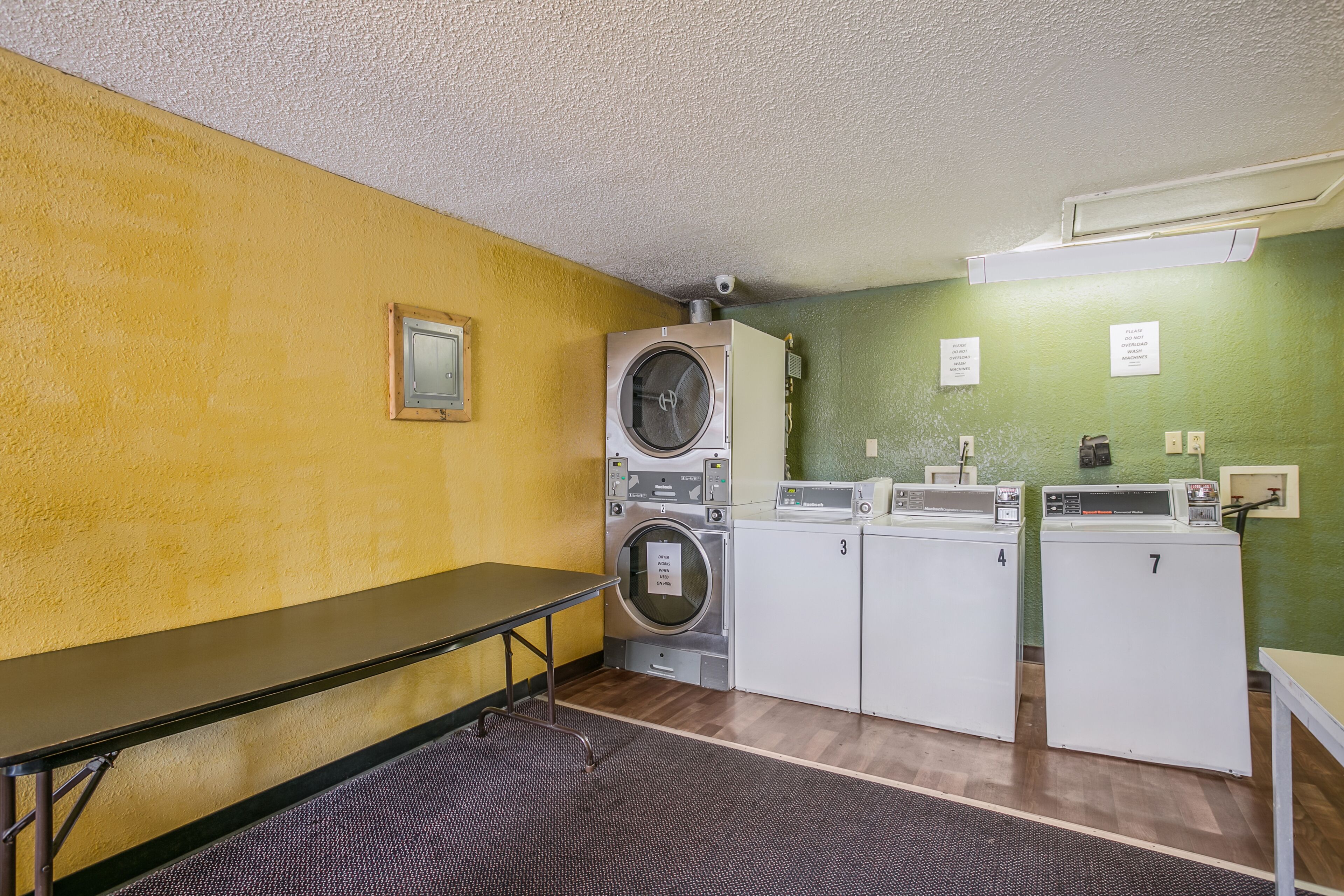 A laundry room with a washing machine, dryers, and a table.