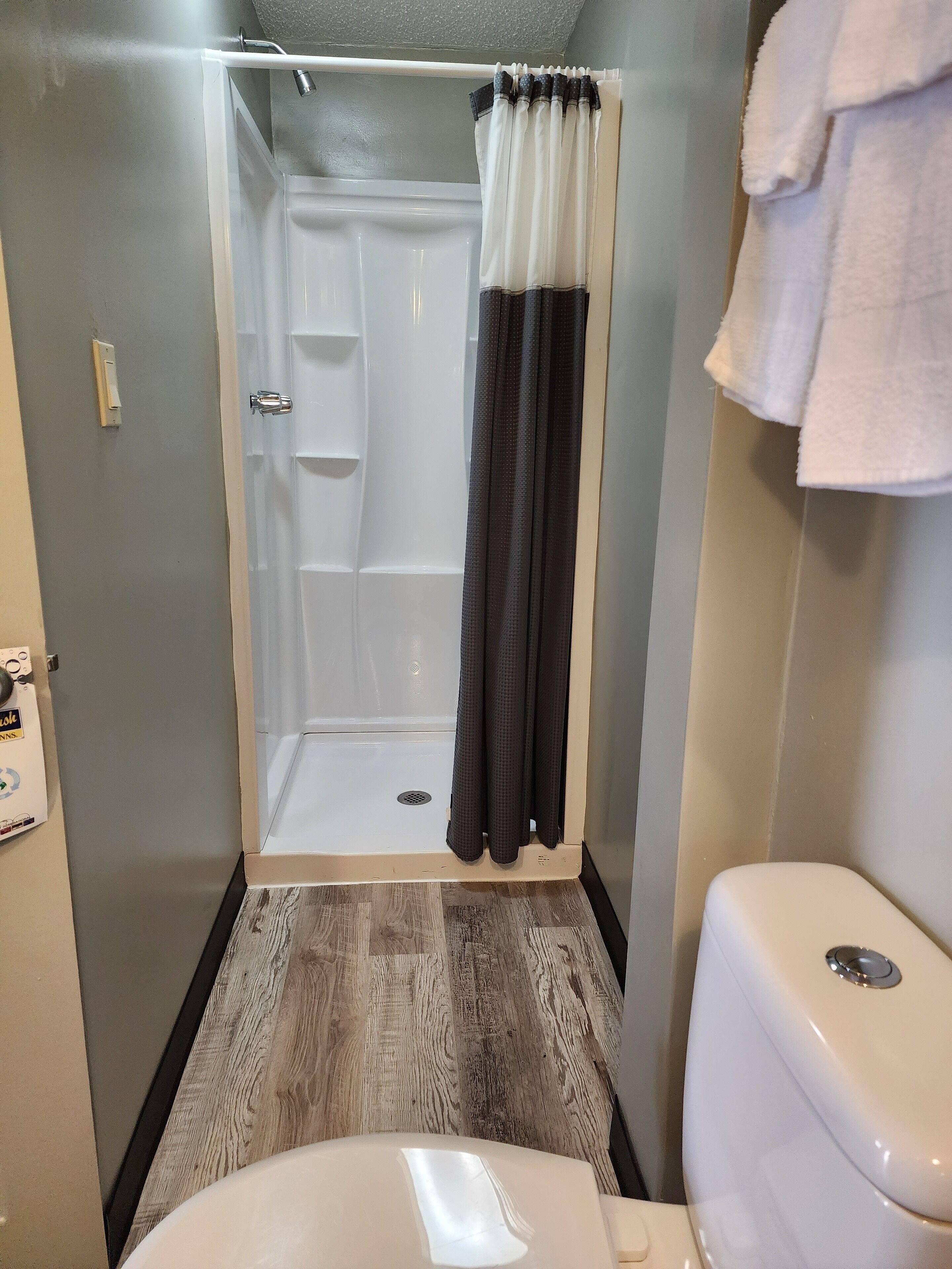 Une petite salle de bain avec une douche, des toilettes et un plancher en bois.