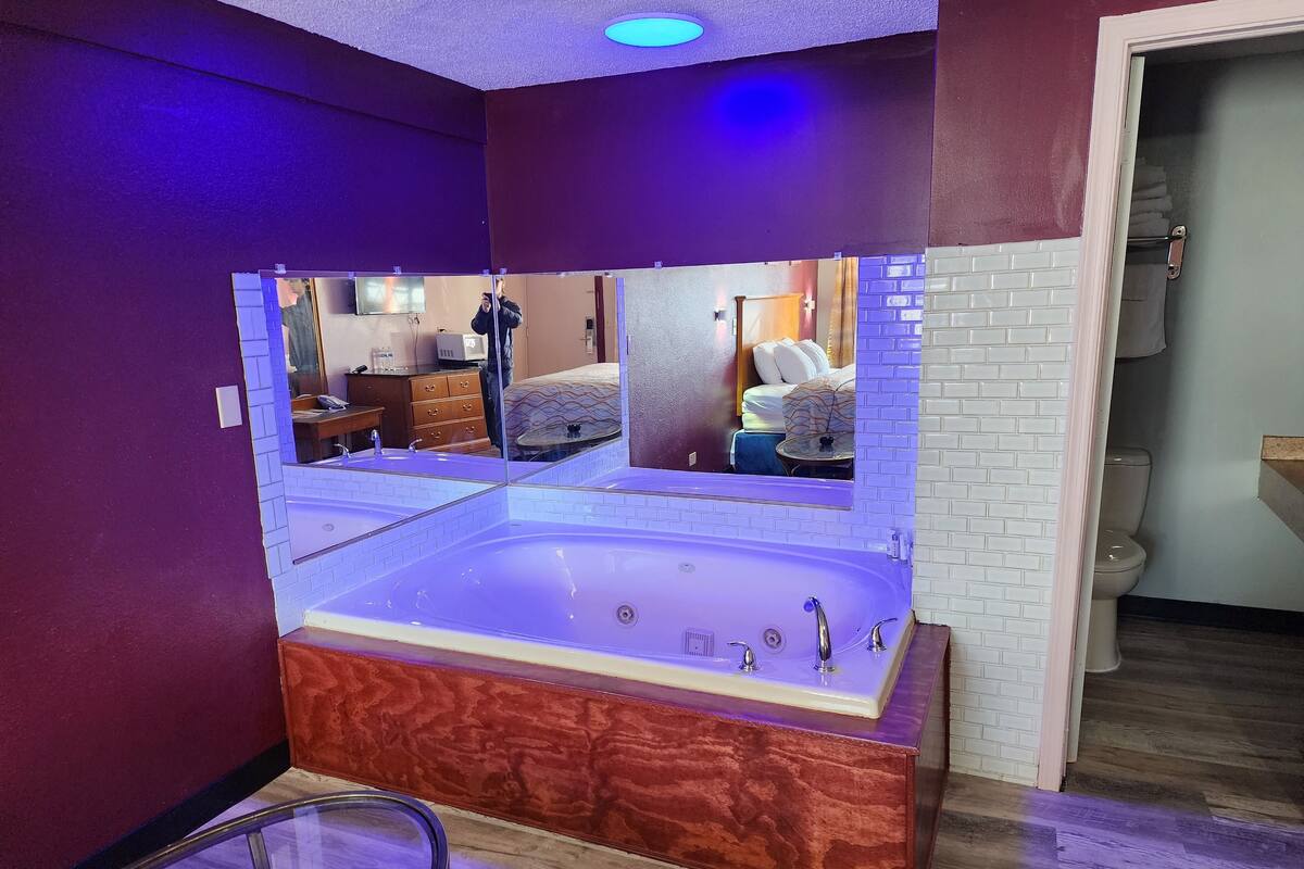 Un baño moderno con una bañera grande, un tocador con espejo y piso de madera.