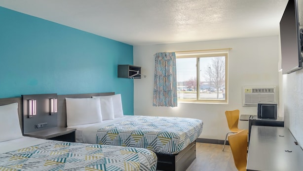 A hotel room with two beds, a desk, a chair, a TV, and a window with a view of the outside. - Motel 6 Sedalia, MO (Sedalia)