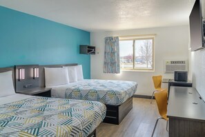 Habitación de hotel con dos camas, un escritorio, una silla, un televisor y una ventana con vistas al exterior.