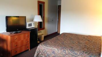 A hotel room with a bed, a television, a microwave, a lamp, and a dresser.