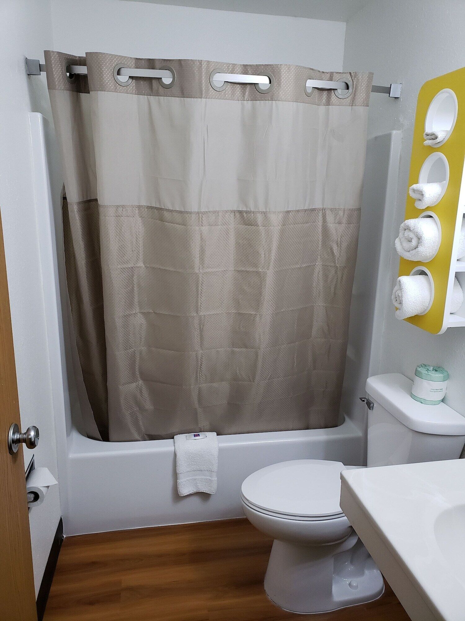 A bathroom with a shower curtain, a toilet, a sink, and a towel rack.