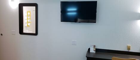 Una habitación con una televisión de pantalla plana montada en la pared, una mesita y dos sillas.