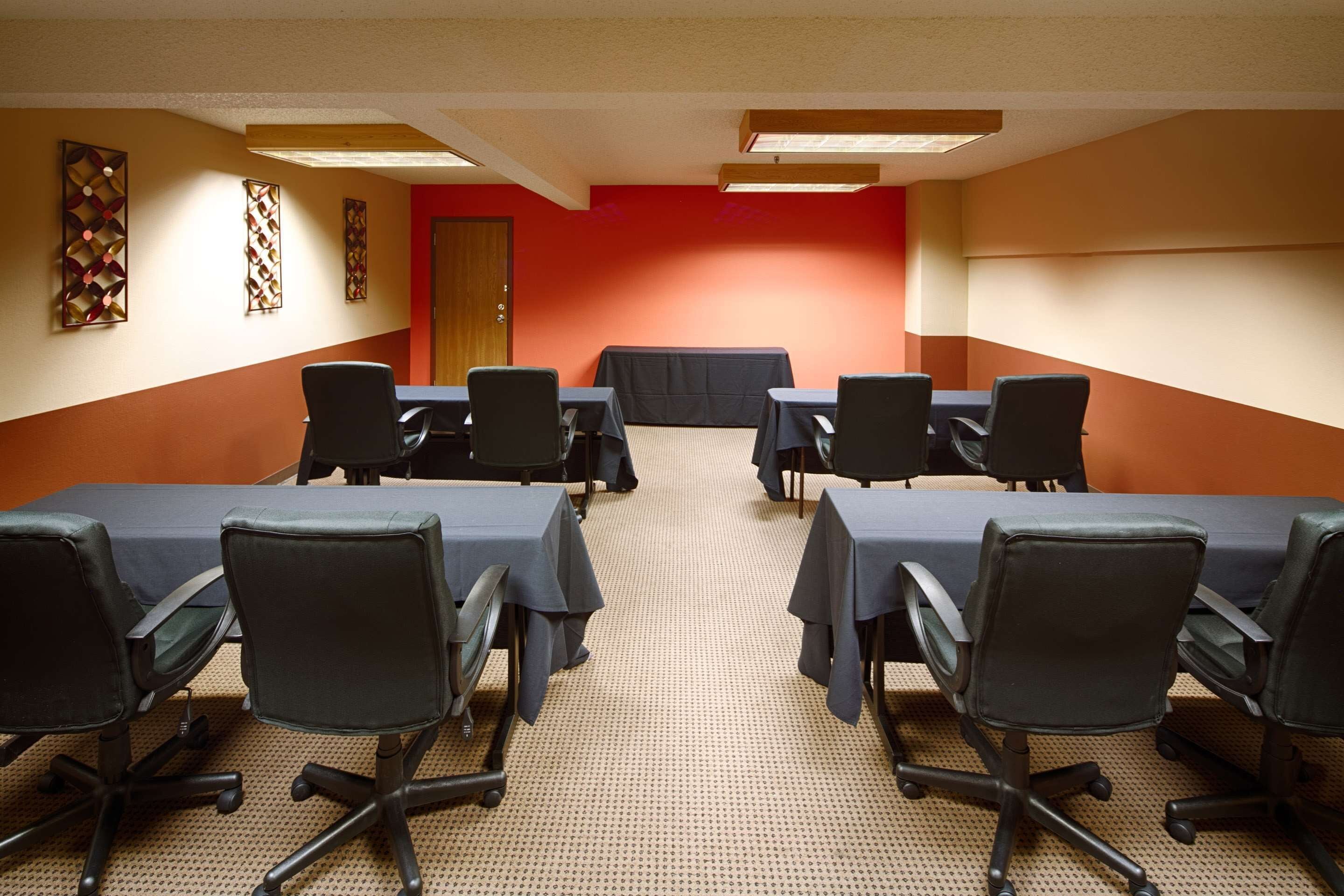 A conference room with a long table, black chairs, and a red accent wall.