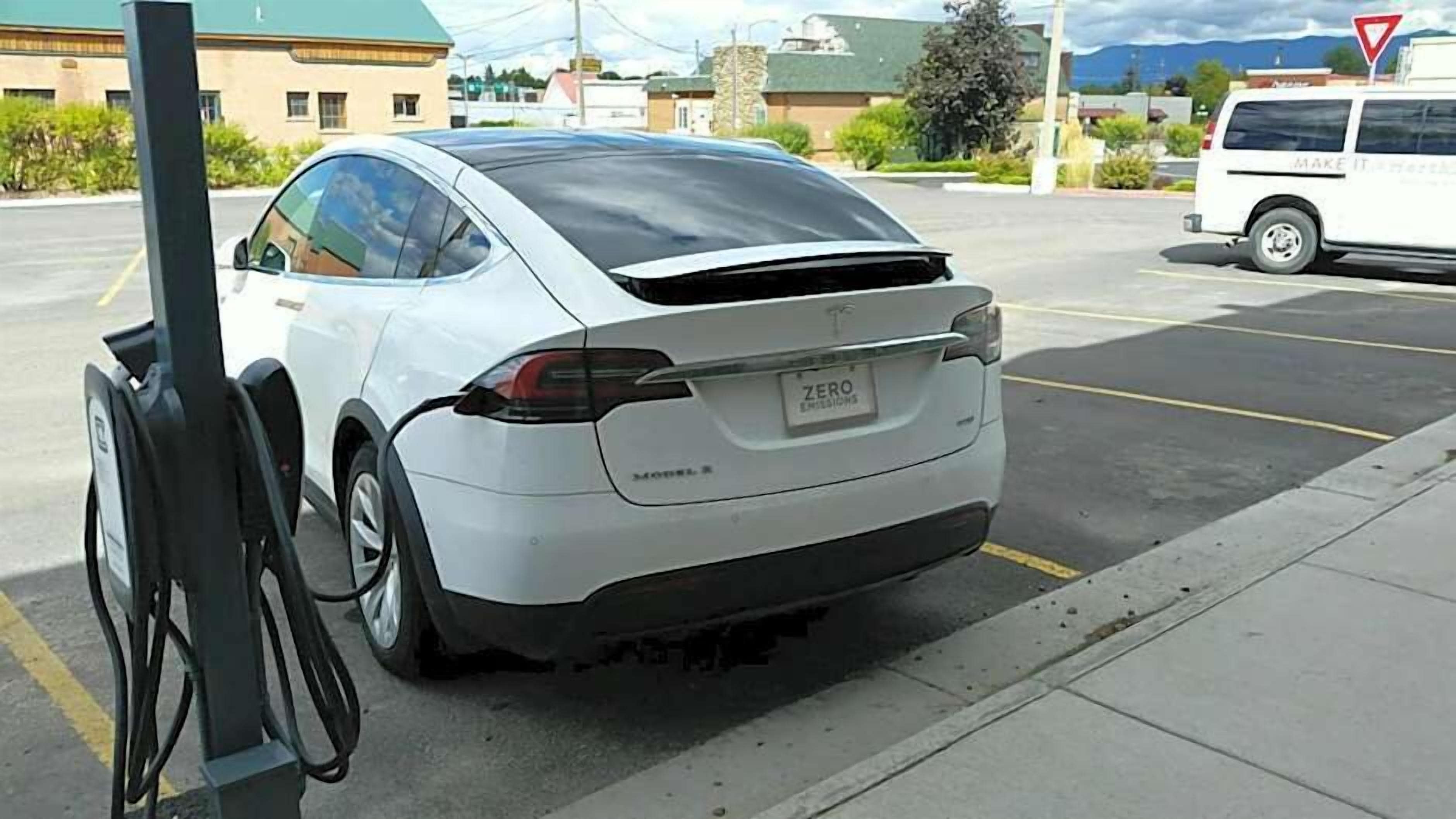 Valkoinen Tesla Model S -auto on pysäköitynä latausasemalle.