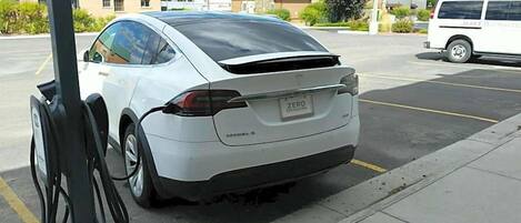 Un Tesla Model S blanco estacionado en una estación de carga.
