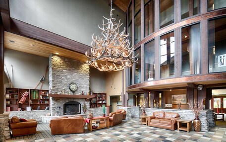 A spacious lobby with a checkered floor, leather sofas, a fireplace, and a large chandelier.