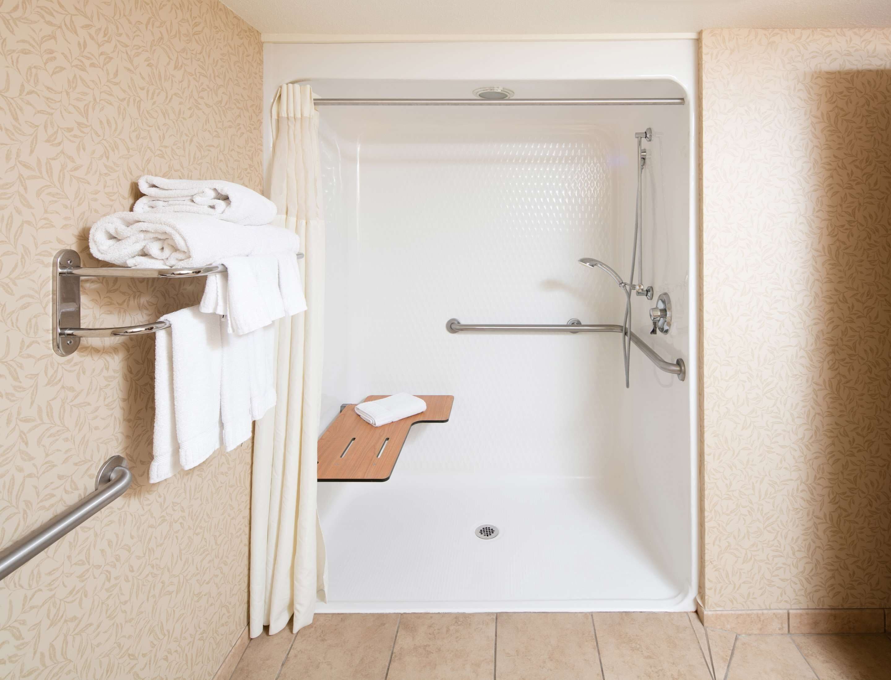 A bathroom with a shower, a towel rack, and a wooden tray.