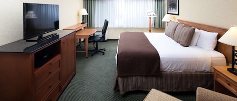 A hotel room with a bed, desk, chair, television, and lamps.