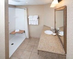 A bathroom with a shower, a sink with a mirror, and a towel rack.