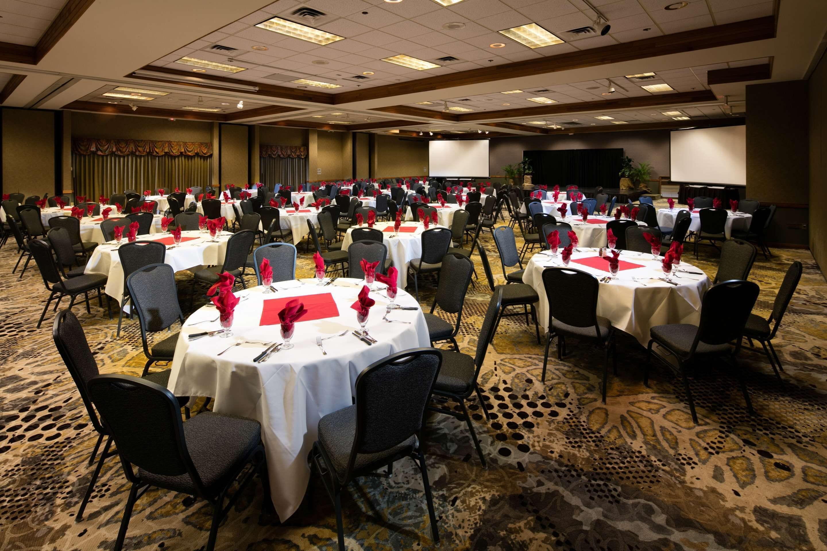 Un amplio salón de banquetes con mesas redondas dispuestas en filas para cenar.