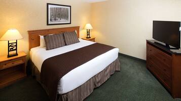 A hotel room with a large bed, two bedside tables with lamps, a television on a wooden cabinet, and a framed picture on the wall.