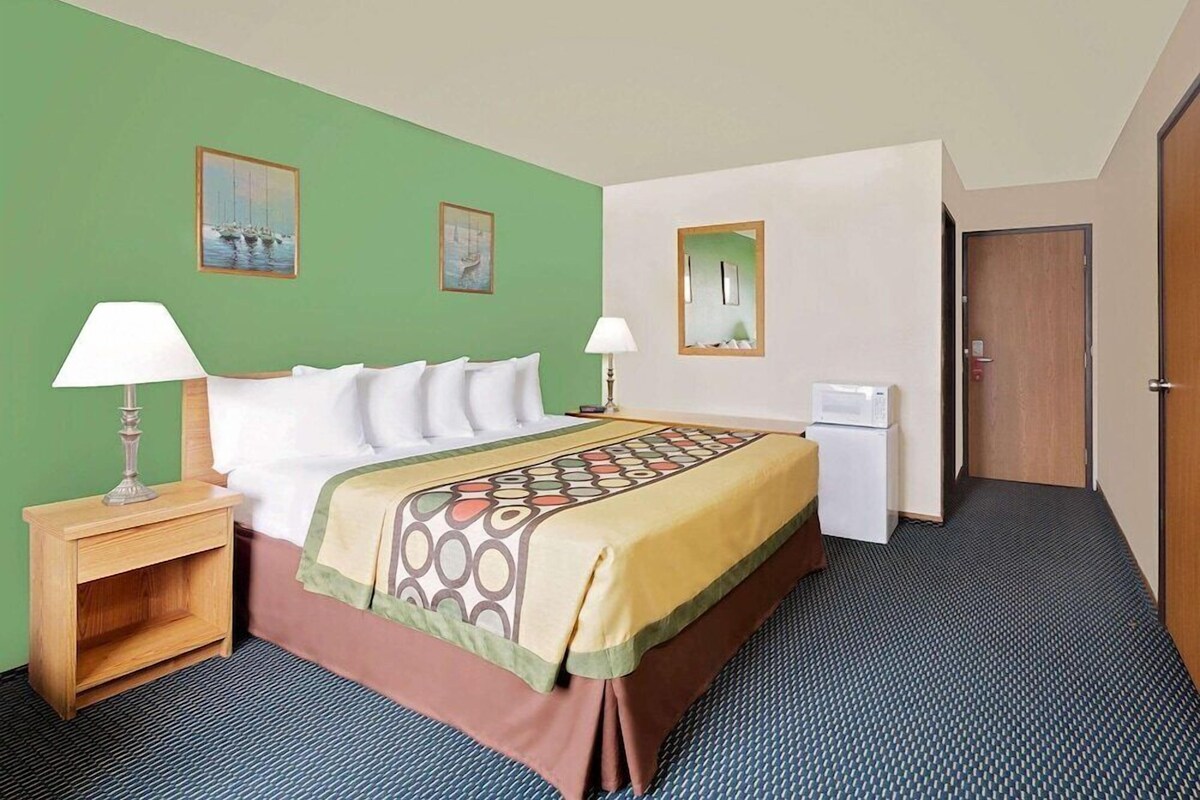 Habitación de hotel con cama, dos mesitas de noche, un escritorio, una silla y una puerta.