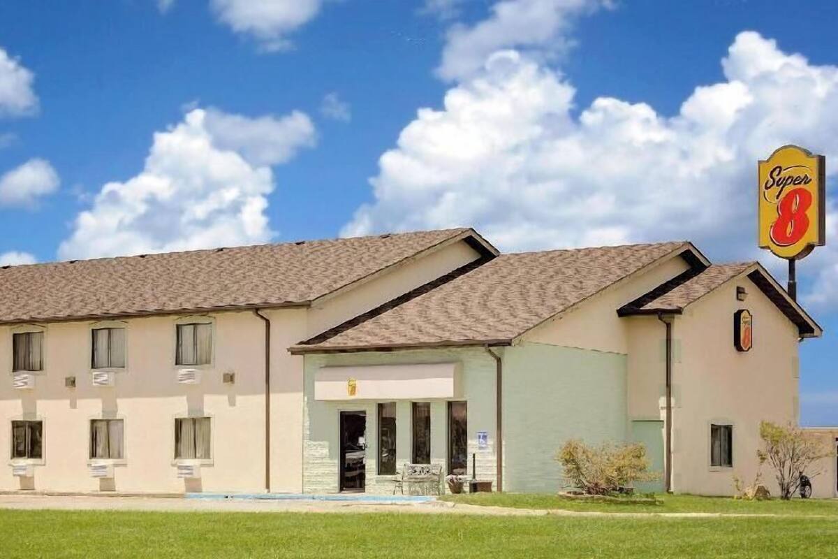 Een motel met een plat dak, een doorgang voor auto's en een bord waarop staat dat het een Super 8 is.