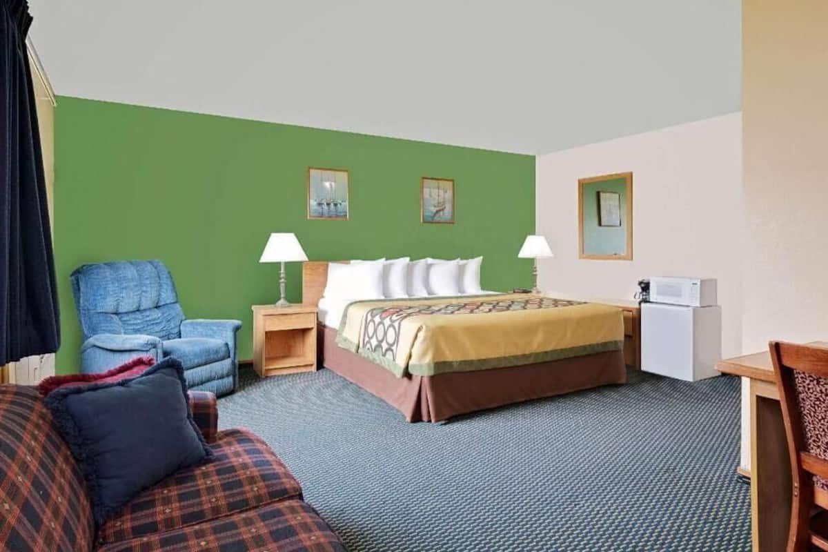 Een hotelkamer met een bed, een stoel, een bank, een bureau en een magnetron.