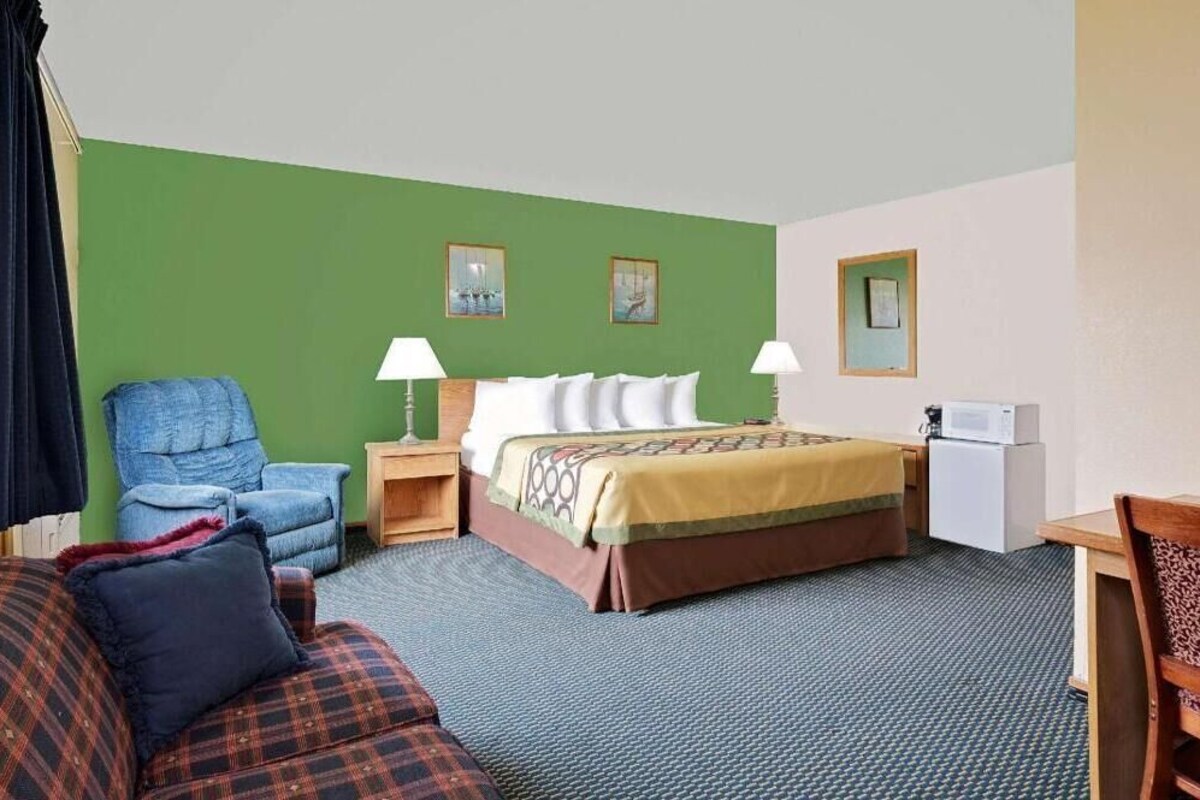 Una habitación de hotel con cama, una silla, un sofá, un escritorio y un microondas.