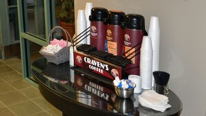 A coffee station with a coffee maker, cups, and a basket of coffee packets. - The Great Falls Inn by Riversage (Great Falls)