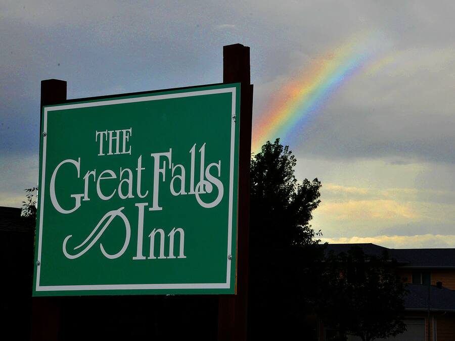 A sign for "The Great Falls Inn" with a rainbow in the background.