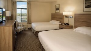 A hotel room with two beds, a desk with a lamp, a chair, and a TV. - The Great Falls Inn by Riversage (Great Falls)