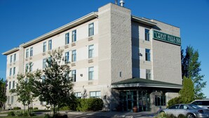 A multi-story hotel with a prominent entrance, a sign reading "The Great Falls Inn," and a parking area with cars.