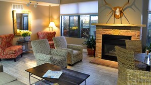 A spacious lounge area with patterned armchairs, a fireplace, and a large mirror.