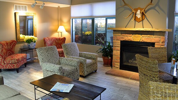 A spacious lounge area with patterned armchairs, a fireplace, and a large mirror. - The Great Falls Inn by Riversage (Great Falls)
