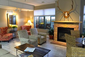 A spacious lounge area with patterned armchairs, a fireplace, and a large mirror.