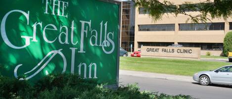 A sign for The Great Falls Inn with a building labeled "Great Falls Clinic" in the background.