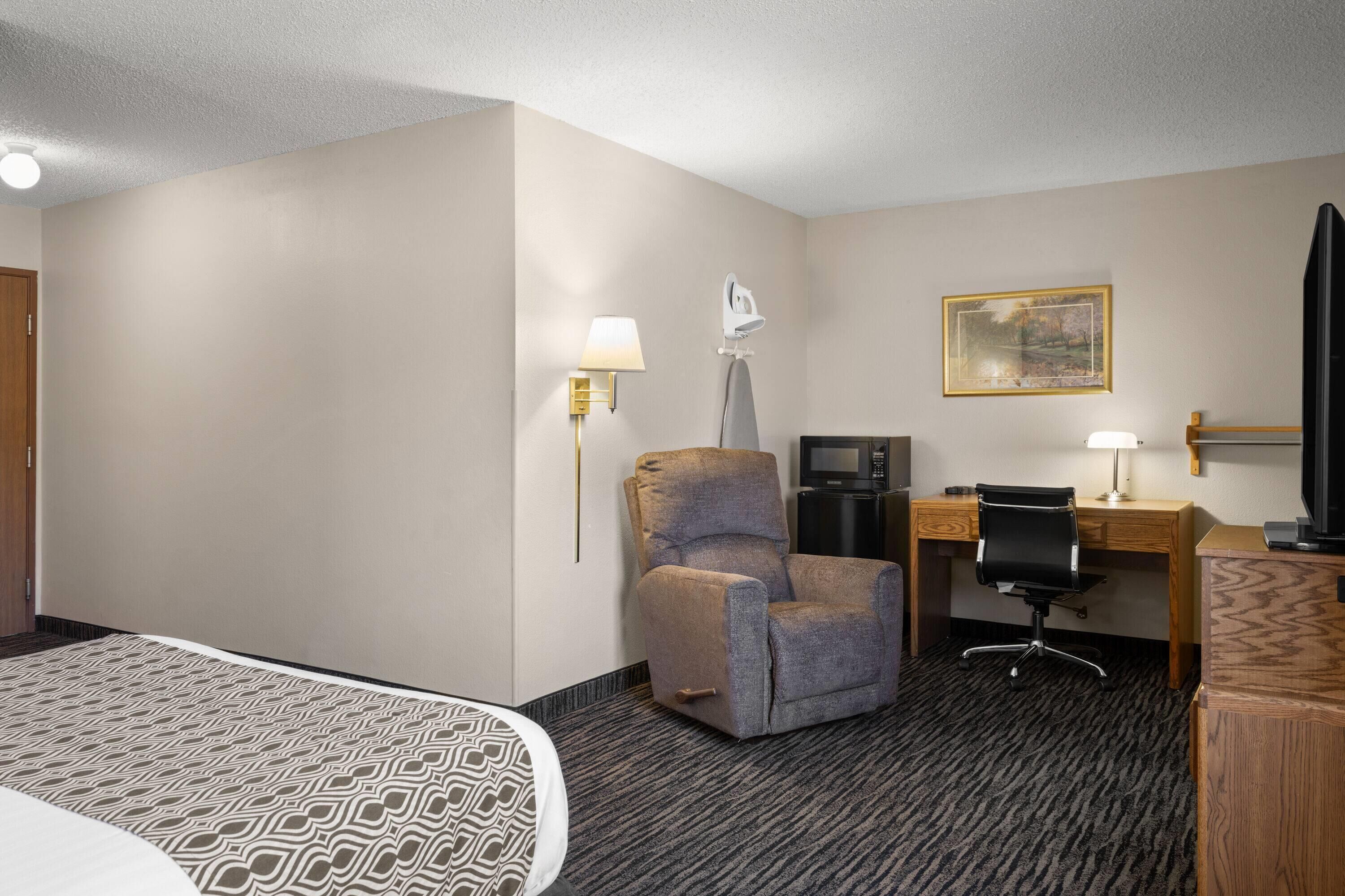 Een hotelkamer met een bed, een bureau, een stoel, een televisie en een schilderij aan de muur.