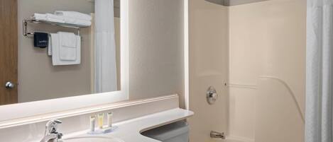 A bathroom with a sink, mirror, towel rack, and shower.