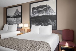A hotel room with two beds, a red chair, a lamp, and two framed pictures of mountains. - Super 8 by Wyndham Lewistown (Lewistown)