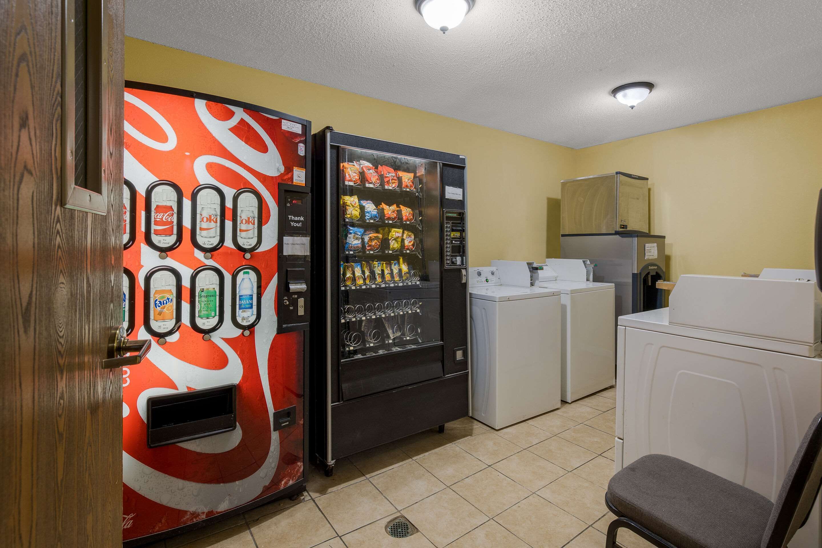 A compact hotel room with a vending machine, a washing machine, and a dryer.