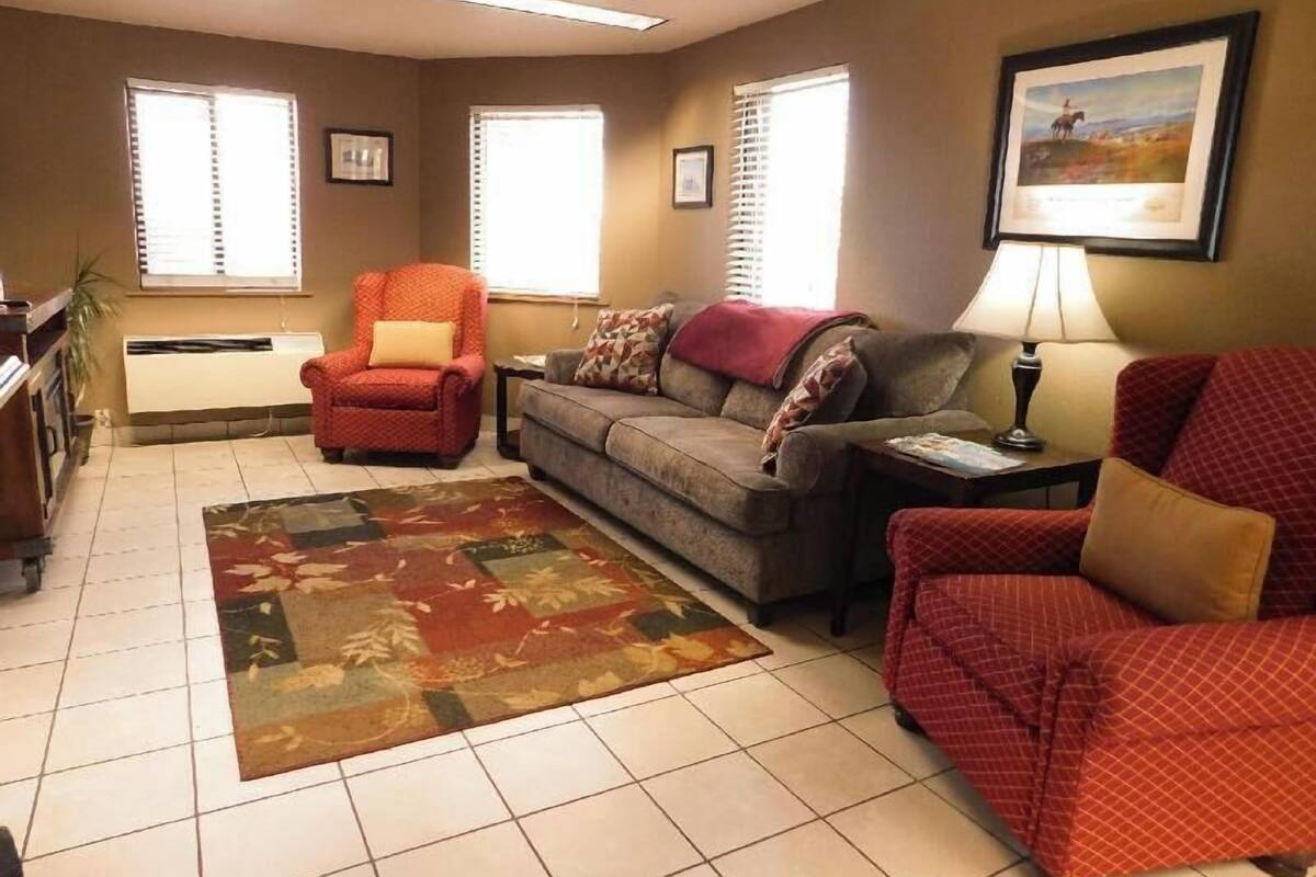 A living room with a sofa, armchairs, a rug, and a painting on the wall.