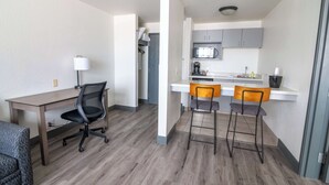 A compact living space with a kitchenette, a dining area with two bar stools, a desk with a chair, and a lamp. - Best Western Helena/Capitol Hotel (Helena)