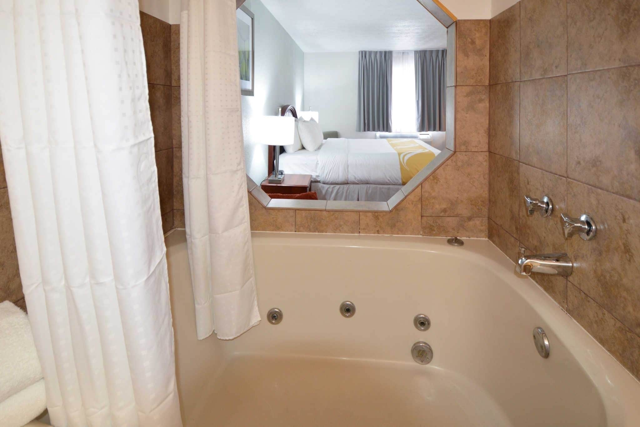 Un baño con una bañera grande, un espejo y un perchero para toallas.