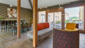 A modern interior with a seating area, a dining space, and large windows offering a view of the outside.
