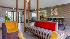 A modern lobby with a red sofa, yellow armchairs, and a patterned bench.