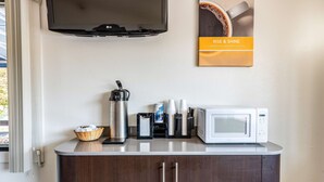 A kitchenette with a microwave, coffee maker, and a basket of bread.