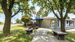 A stone building with a blue awning and a flag, surrounded by trees and benches.