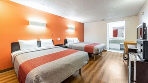 A hotel room with two beds, a TV, and a window with a view of a bathroom.