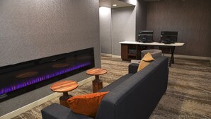 Un espace de détente moderne doté d’une cheminée intégrée, de sièges et d’une petite table.
