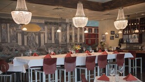 Un restaurant où de nombreuses tables sont dressées pour le service, chacune étant agrémentée de serviettes rouges et de verres à vin.