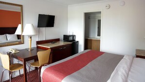 A hotel room with a bed, a desk with a telephone, a chair, a television, and a microwave. - Motel 6 - Dayton, OH (Dayton)