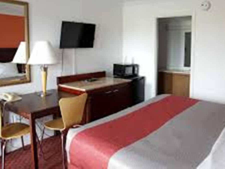 Habitación de hotel con cama, escritorio con silla, televisión y armario.