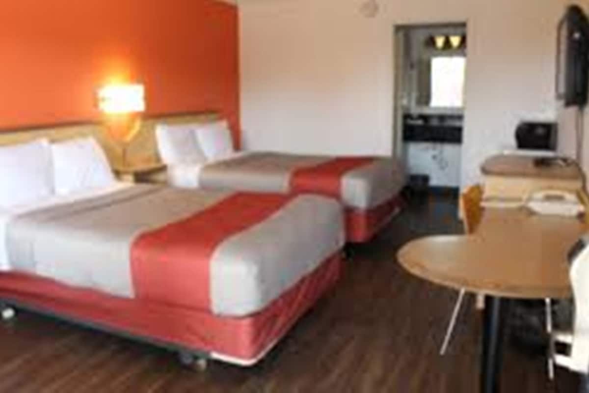 Habitación de hotel con dos camas, un escritorio y una silla.