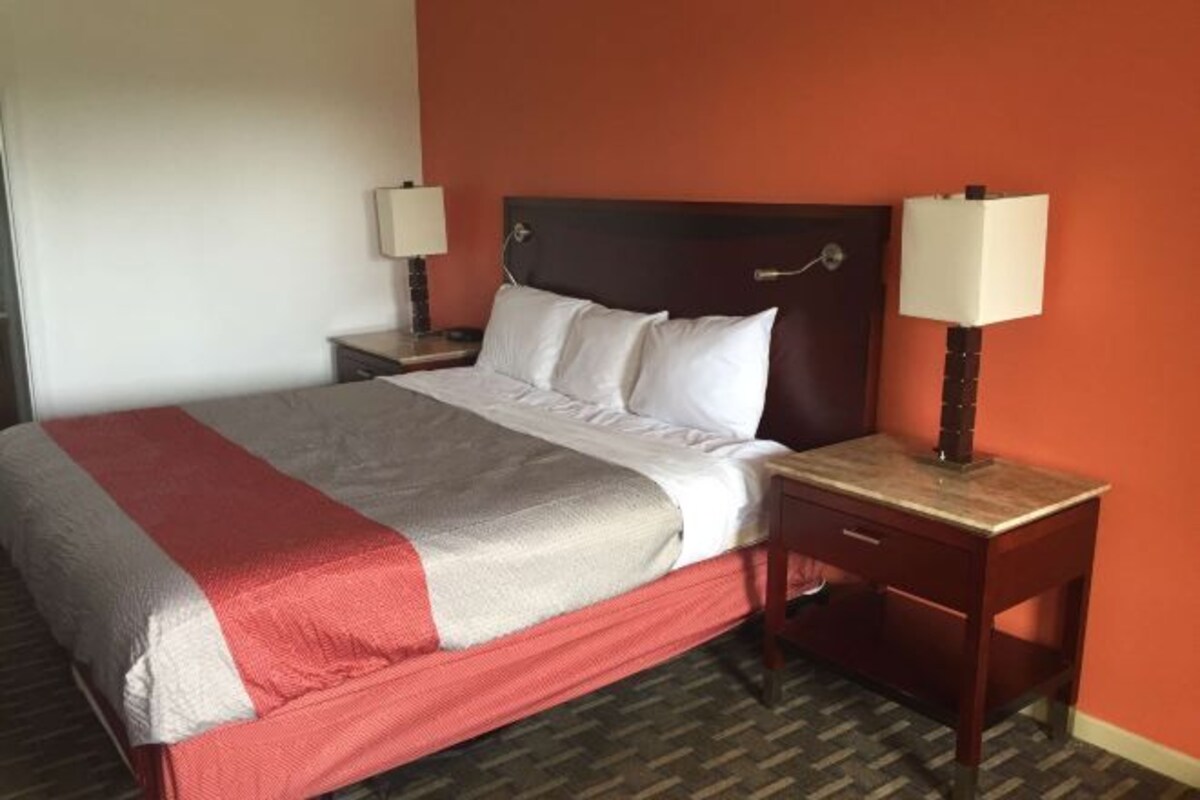 A hotel room with a bed, two bedside tables, and a nightstand.