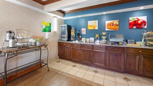 A breakfast bar with a coffee pot, fruit bowl, and various breakfast items.