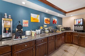 A kitchen with a coffee machine, waffle maker, microwave, and a TV. - Quality Inn Meadville (Meadville)